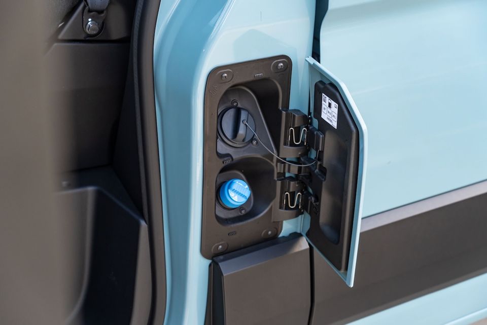 Close-up of the open fuel filler door on a light blue 2026 Renault Master, showing the diesel filler cap and blue AdBlue cap.