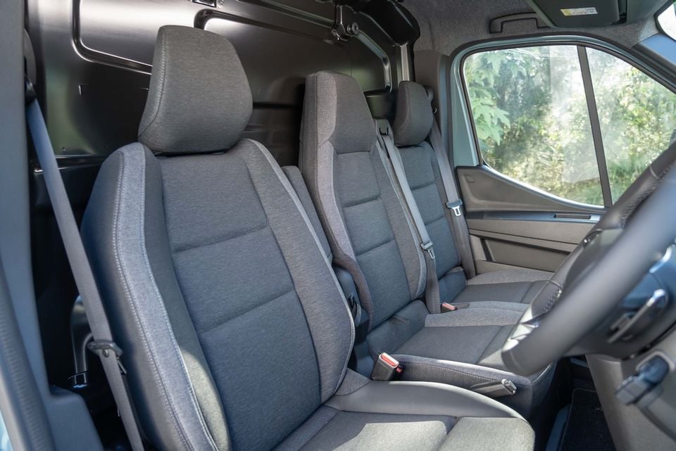 Interior view of the 2026 Renault Master van showing the front bench-style seating with grey fabric upholstery and seatbelts visible