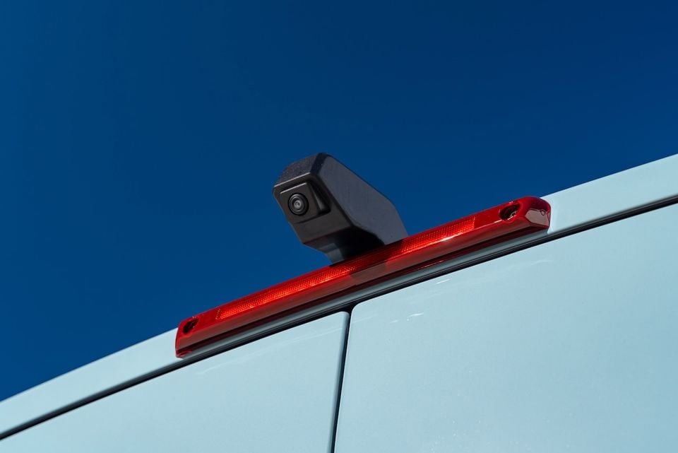 Rear-mounted reversing camera and high-mounted brake light on the roof of a 2026 Renault Master van, seen against a clear blue sky