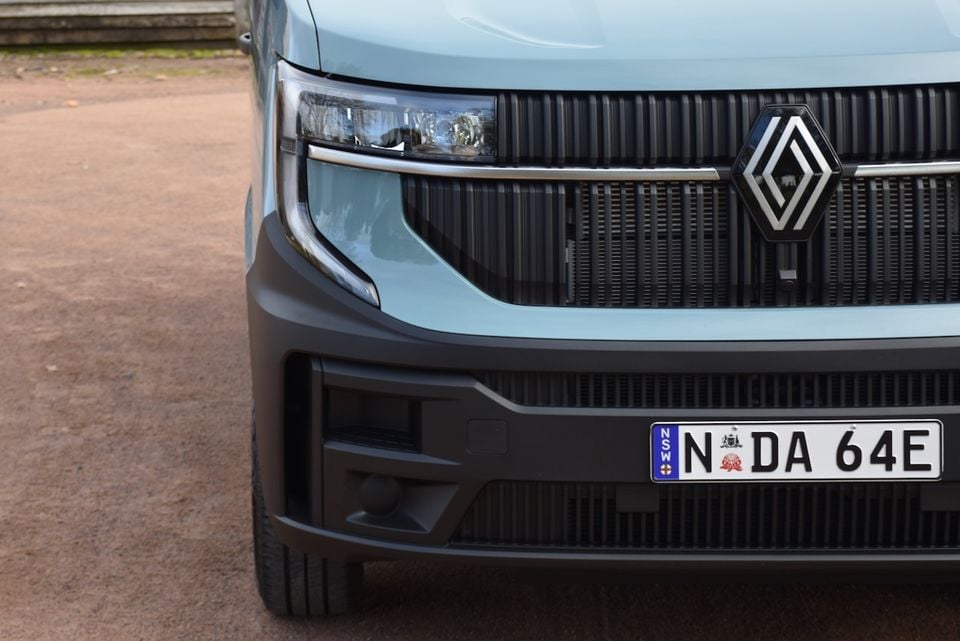 Close-up of the front grille and headlight of a light blue 2026 Renault Master van, showing the Renault diamond badge and NSW number plate