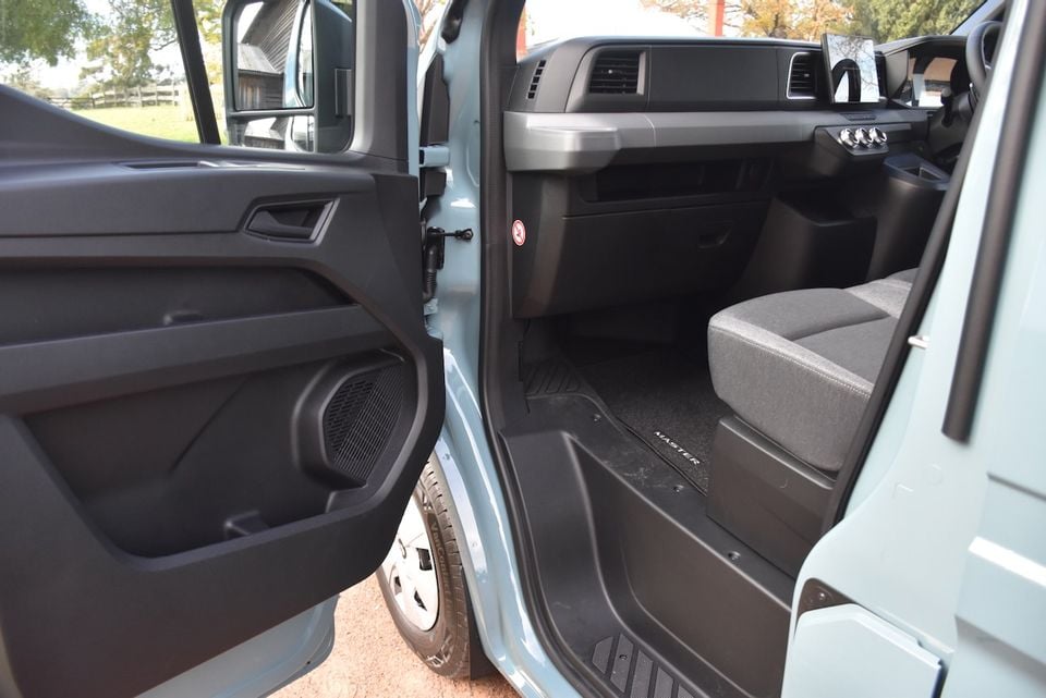 Interior of a 2026 Renault Master van with the driver's door open, showing the door panel, floor mat with 'Master' branding, dashboard, and front seat