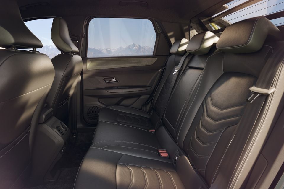 The rear seats of a 2026 Renault Niagara SUV, trimmed in black leather with contrast stitching, viewed from the side door opening with a mountain vista through the window