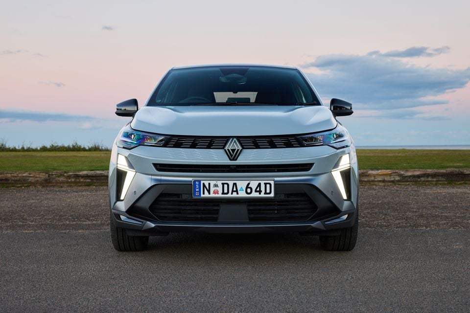 Front view of a silver 2026 Renault Symbioz SUV with NSW plates, parked near a coastal area at dusk