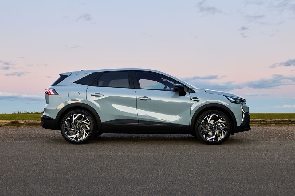 A light green 2026 Renault Symbioz Esprit Alpine small SUV seen from the side, parked on a road at dusk