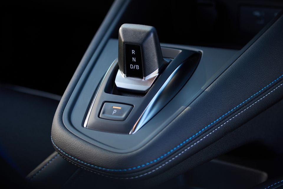 Close-up of the gear selector and park button on the centre console of a 2026 Renault Symbioz Esprit Alpine, with blue contrast stitching on the leather armrest