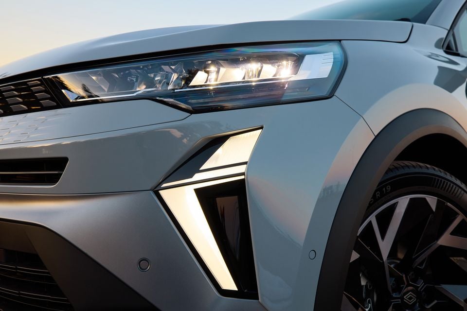 Close-up of the front corner of a 2026 Renault Symbioz Esprit Alpine, showing the LED headlight and illuminated front bumper accent in silver