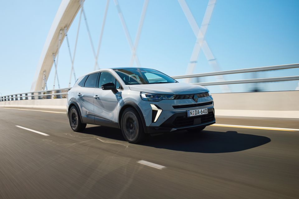 A grey 2026 Renault Symbioz Esprit Alpine SUV driving across a bridge on an Australian road, seen from the front-side
