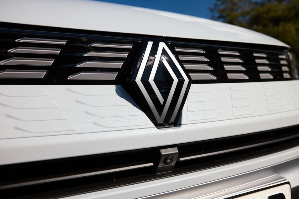 Close-up of the Renault diamond badge on the front grille of a white 2026 Renault Symbioz
