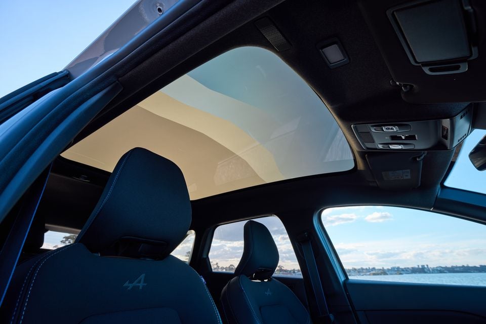 Interior view of a 2026 Renault Symbioz Esprit Alpine showing the panoramic glass roof, blue Alpine-badged seats and overhead controls