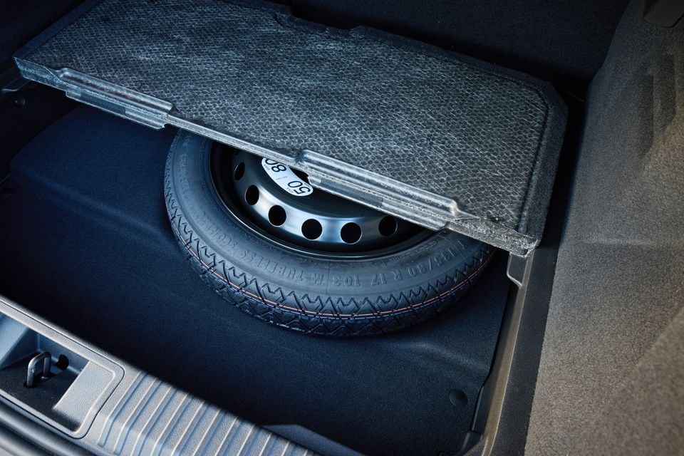 A spare wheel stored beneath the boot floor of a 2026 Renault Symbioz, with the carpet panel lifted to reveal the compact spare tyre.
