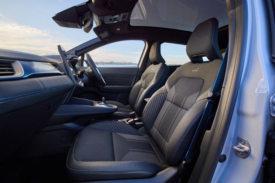 Interior view of the 2026 Renault Symbioz Esprit Alpine showing the front seats with blue stitching and Alpine logo embroidery, dashboard, and centre console