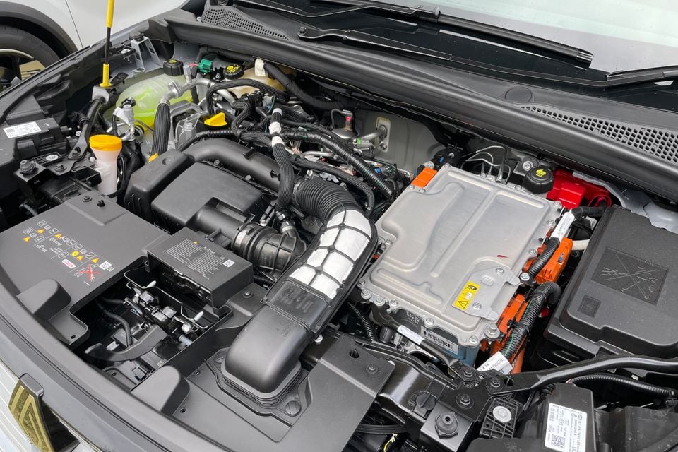 The engine bay of a 2026 Renault Symbioz full hybrid, showing the combustion engine alongside hybrid electric components including an inverter and orange high-voltage wiring.