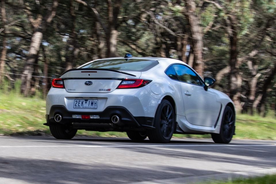 A white Subaru BRZ tS coupe seen from the rear three-quarter angle while driving on a tree-lined road in Victoria, Australia