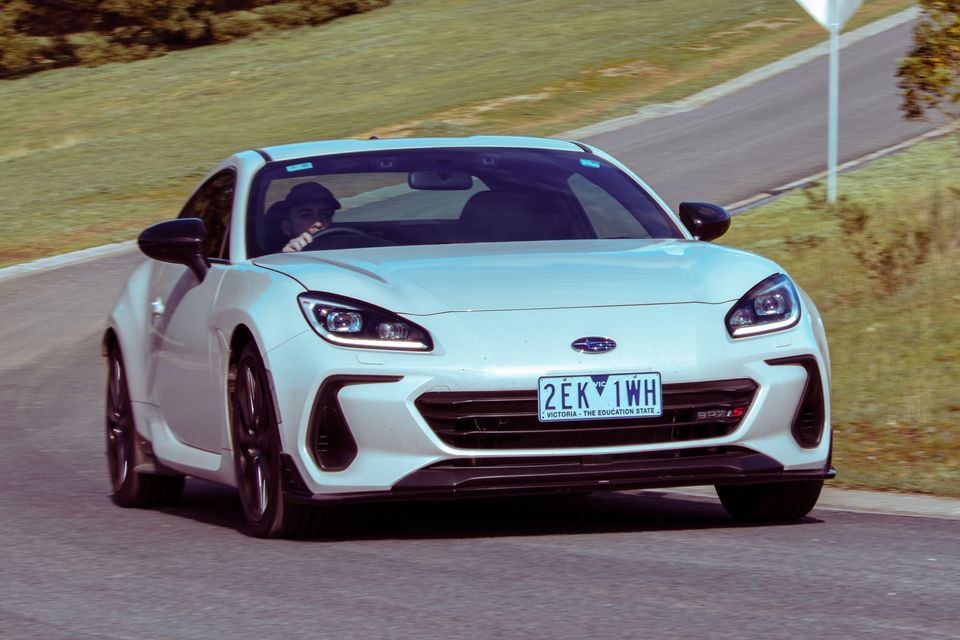 A white Subaru BRZ S coupe driving on a road, seen from the front