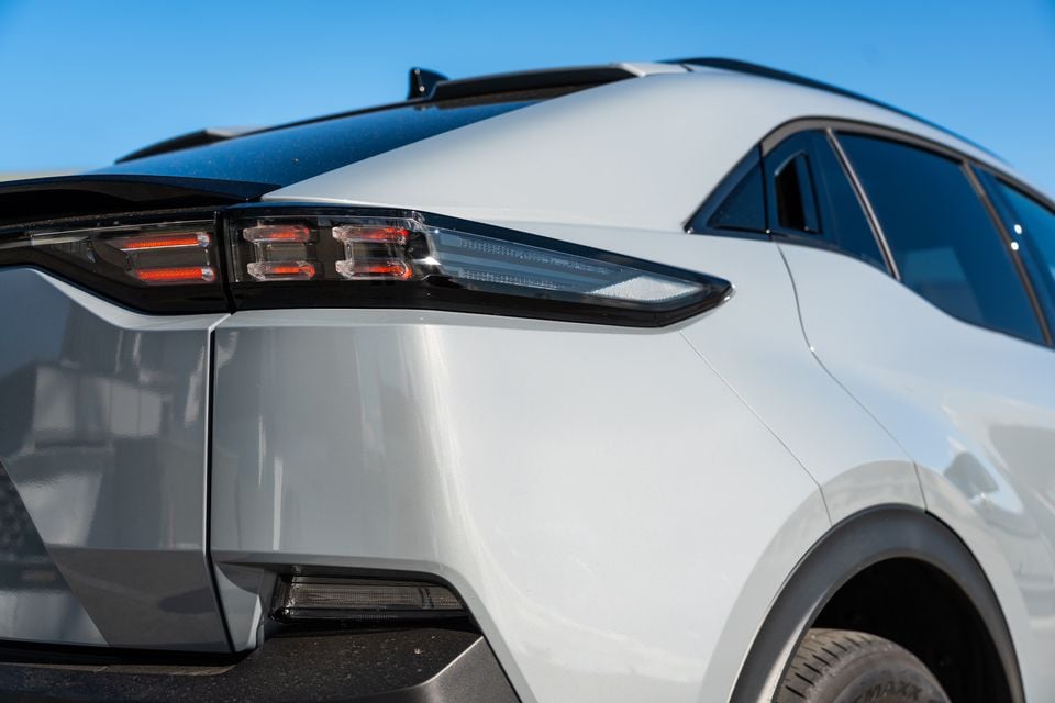 Close-up of the rear tail light and quarter panel of a white 2026 Subaru Outback SUV against a clear blue sky