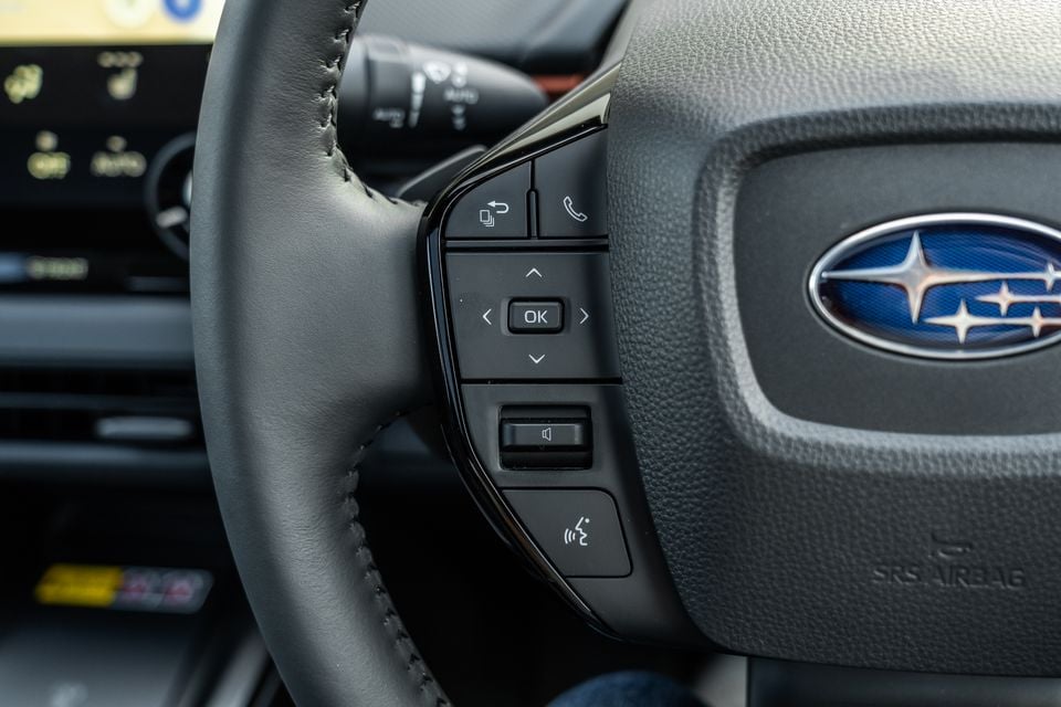 Close-up of the Subaru Forester steering wheel controls showing media, phone, navigation and driver assistance buttons alongside the Subaru badge