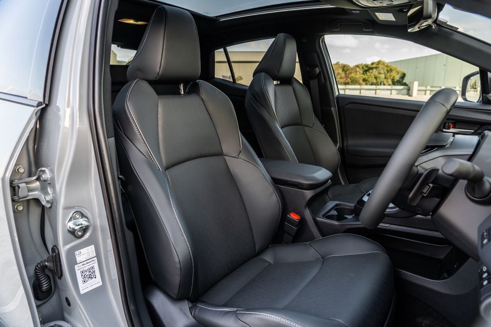 Interior view of a Subaru showing black leather front seats, centre console, and steering wheel with the driver's door open