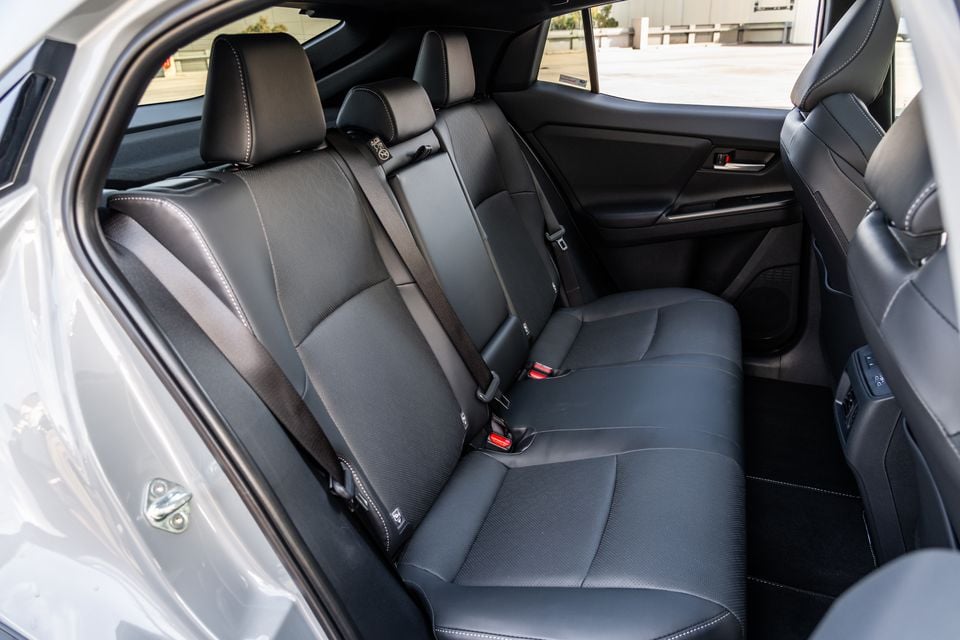 Rear seat interior of a Subaru SUV showing black fabric and leather upholstery with three seatbelts, viewed through the open rear door