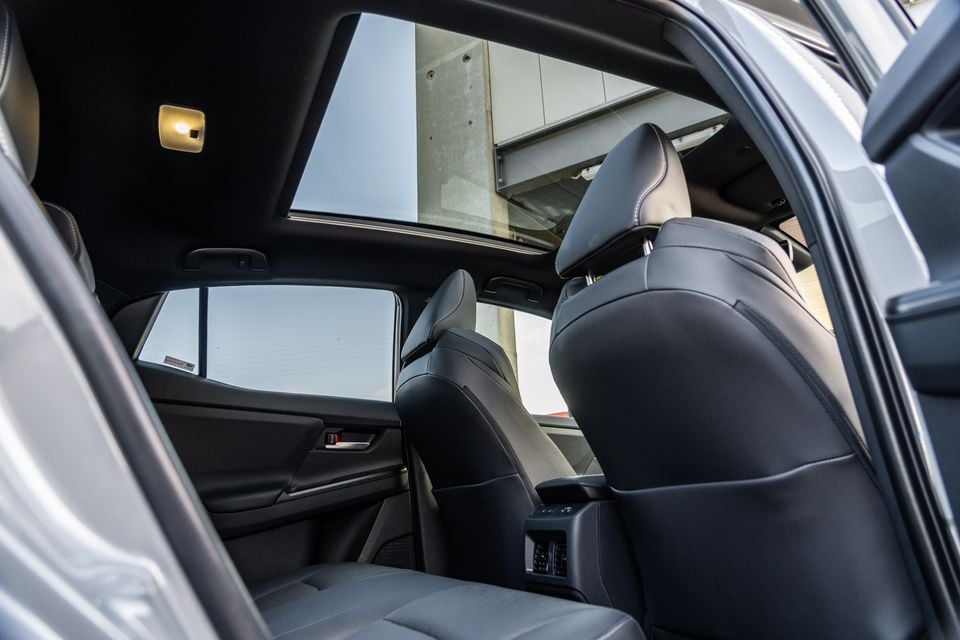 Rear interior of a Subaru SUV showing dark leather rear seats and a large panoramic sunroof open overhead, viewed through the open rear door
