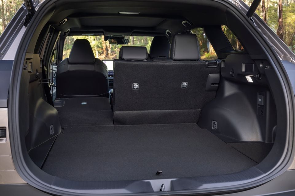 Boot interior of the 2026 Toyota bZ4X PHEV SUV with rear seats folded flat, showing a large, flat cargo area with a forest visible through the rear window