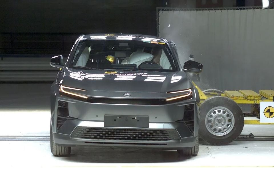 A Toyota C-HR SUV during a Euro NCAP side-impact crash test, seen from the front with airbags deployed and a crash barrier to the right