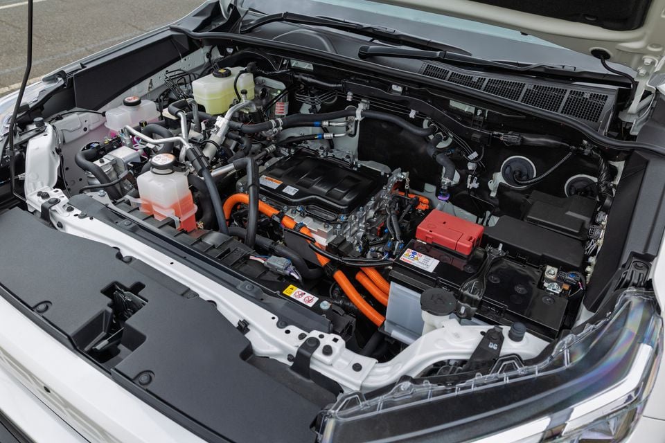 Engine bay of a 2026 Toyota HiLux BEV showing the hybrid powertrain with distinctive orange high-voltage cables and components under an open bonnet