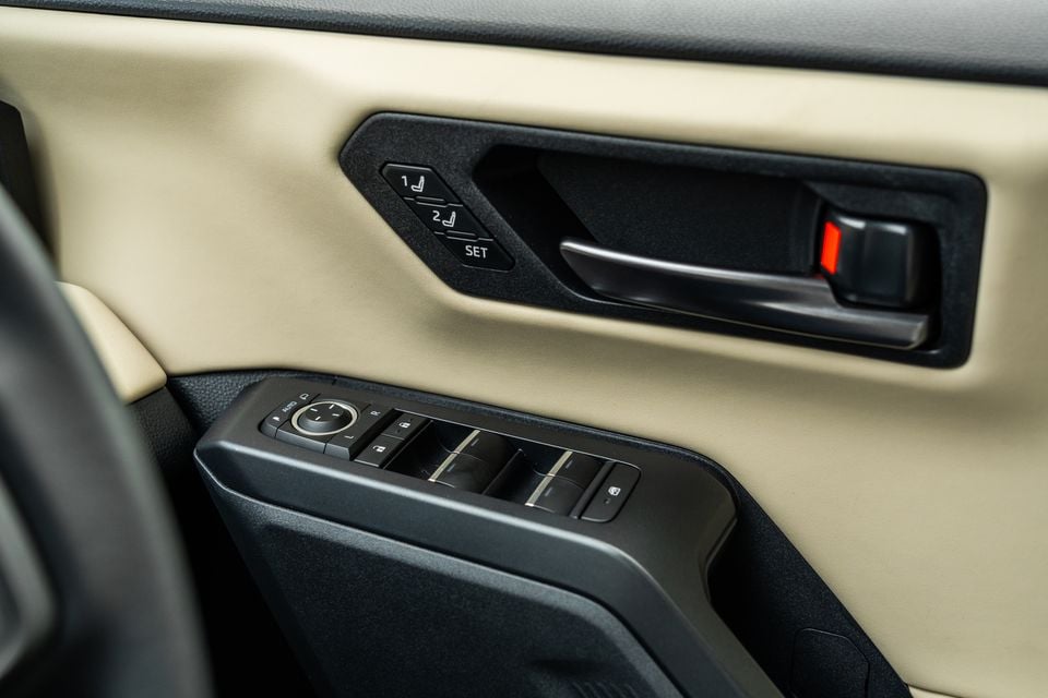 Close-up of the door panel controls in a 2026 Toyota RAV4 Cruiser, showing memory seat buttons, door handle and window switches