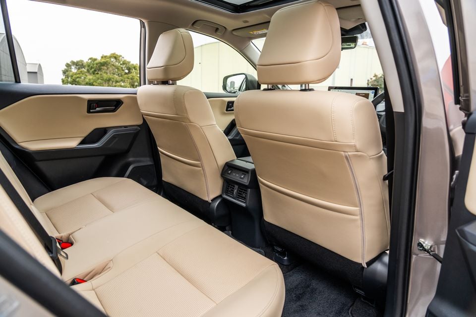 The rear seats of a 2026 Toyota RAV4 Cruiser, shown in tan leather with rear air vents and a fold-down armrest.