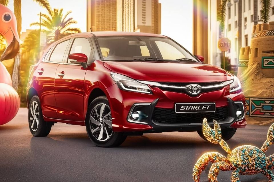 A red Toyota Starlet hatchback seen from the front-side angle, set against a colourful summer-themed backdrop with palm trees and decorative elements.