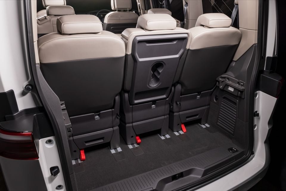 Interior boot area of a 2026 Volkswagen Multivan showing folded third-row seats with ISOFIX anchor points and a flat cargo floor, viewed from the open rear tailgate