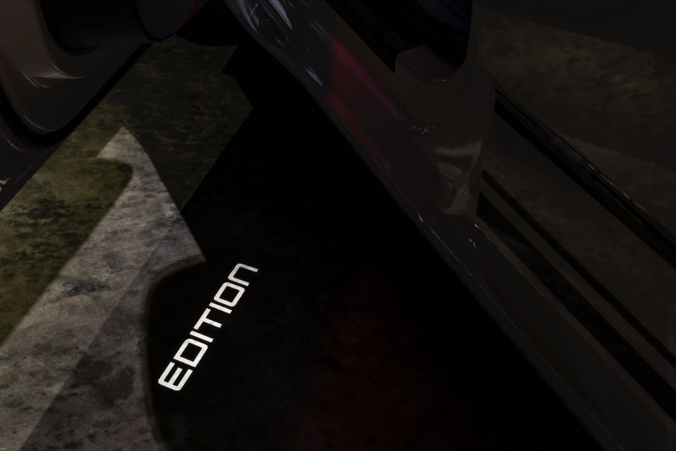 A door puddle light projecting the word 'EDITION' onto the ground beside an open car door on a 2026 Volkswagen Multivan Edition