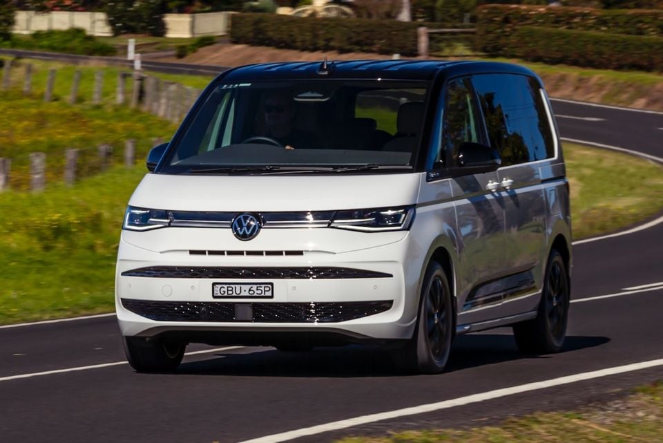 A white 2026 Volkswagen Multivan van seen from the front while driving on a country road