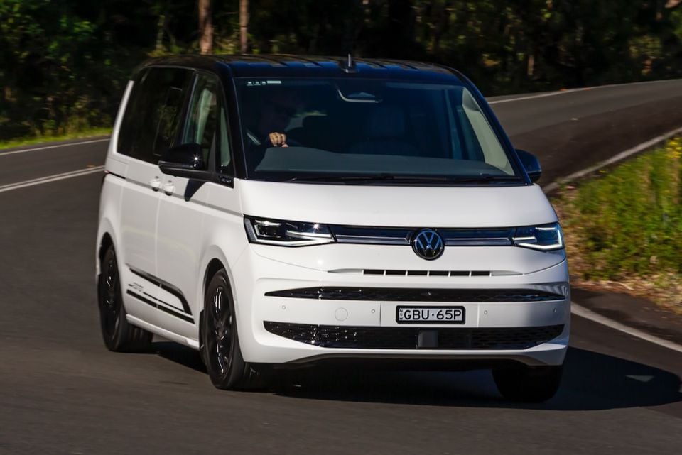 A white 2026 Volkswagen Multivan Edition driving on a road, seen from the front