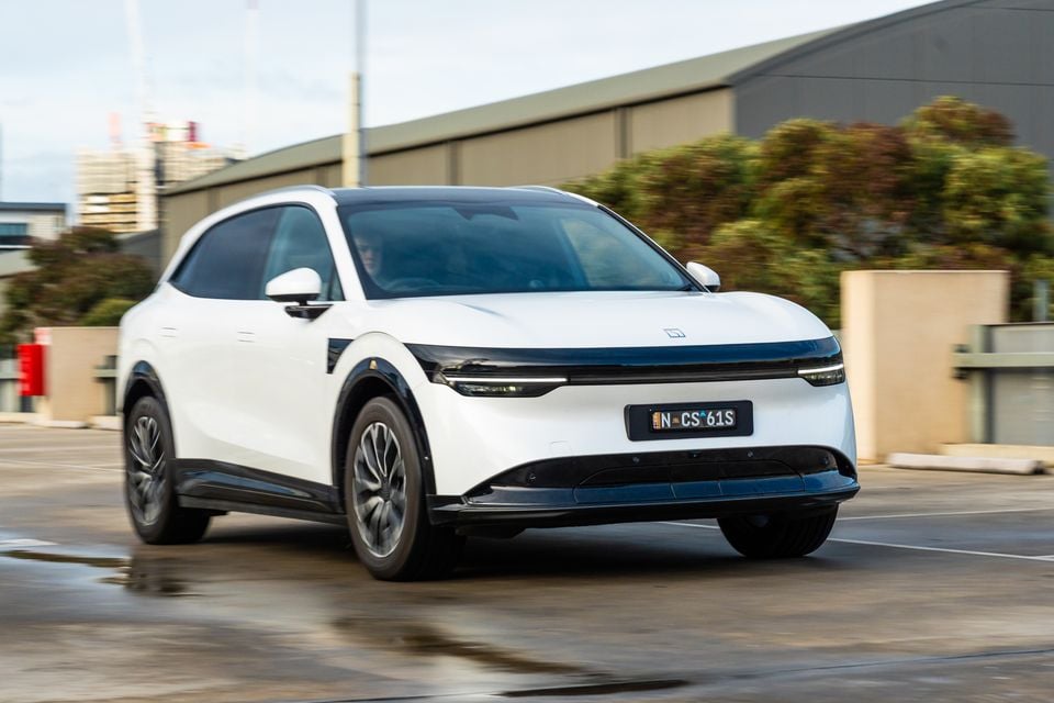 Um SUV elétrico Zeekr 7X 2026 branco dirigindo em uma estrada, visto do ângulo frontal.