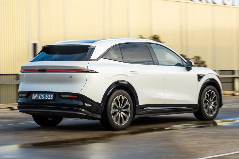 A white 2026 Zeekr 7X electric SUV seen from the rear three-quarter angle while driving on a road