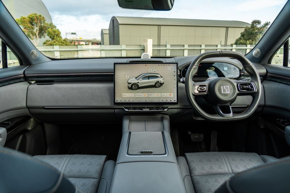 Interior of the 2026 Zeekr 7X showing the dashboard, large central touchscreen displaying a car configurator, steering wheel, and grey leather seats