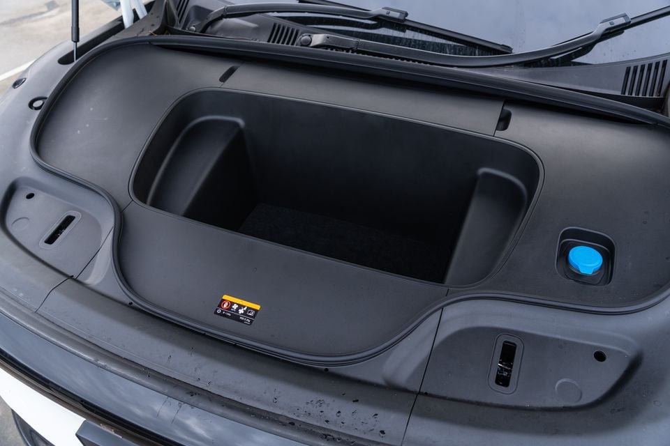 The front storage compartment (frunk) of a 2026 Zeekr 7X, open and empty, showing a large cargo bin with a blue fluid cap visible to the right