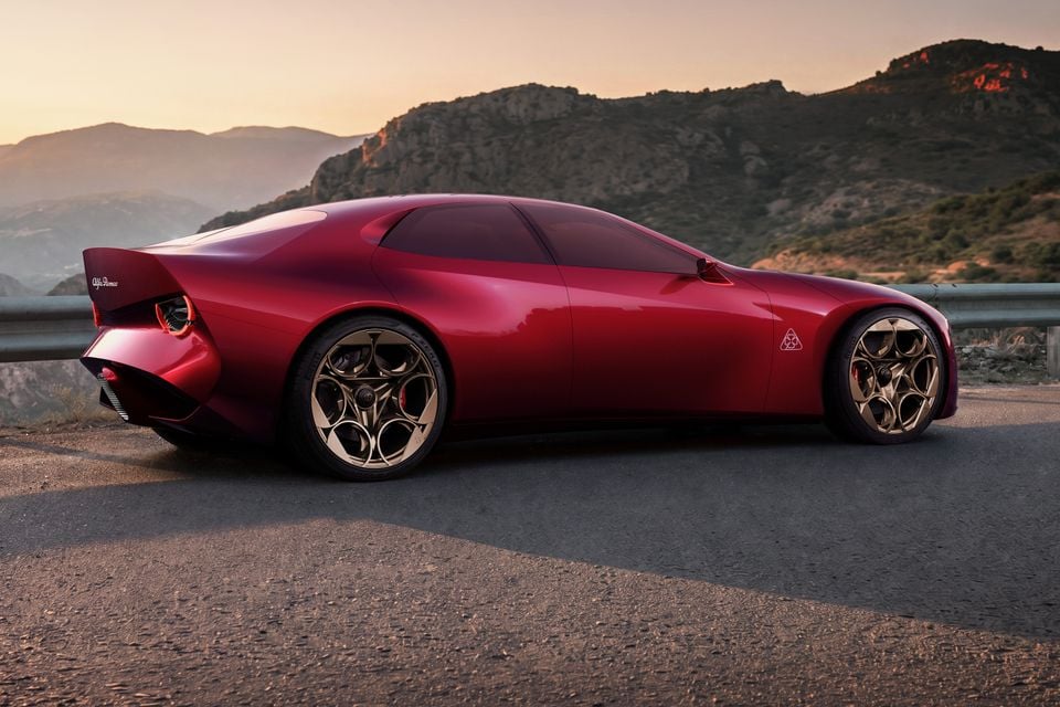 A red 2026 Alfa Romeo Cuorerosso coupe seen side-on, parked on a mountain road at sunset