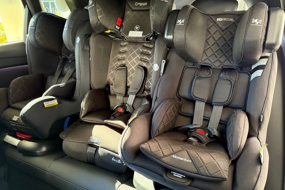 Three child car seats installed side by side across the rear seat of a vehicle, including InfaSecure Momentum and other models