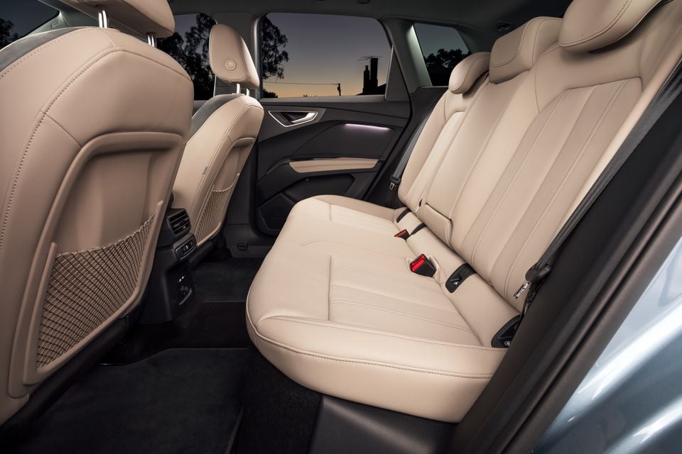 Beige leather rear seats of a 2026 Audi Q4 e-tron, viewed from the side door opening at dusk