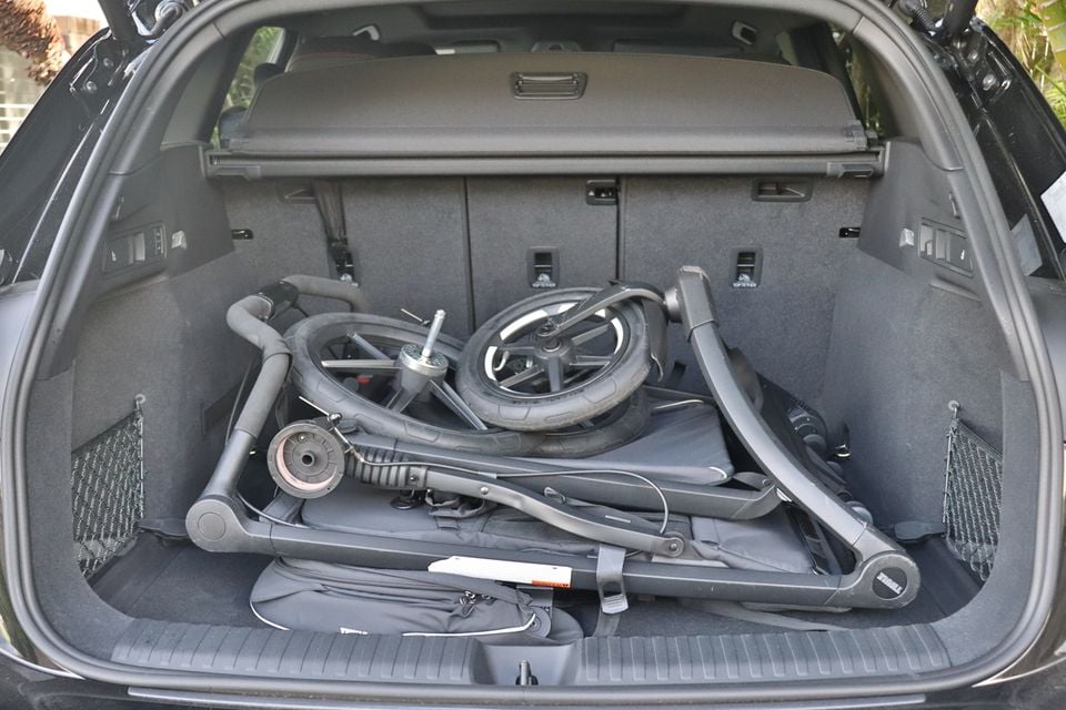 A folded pram stored in the boot of a 2026 Audi SQ6 e-tron, showing the cargo space with the rear seats up and a cargo blind extended