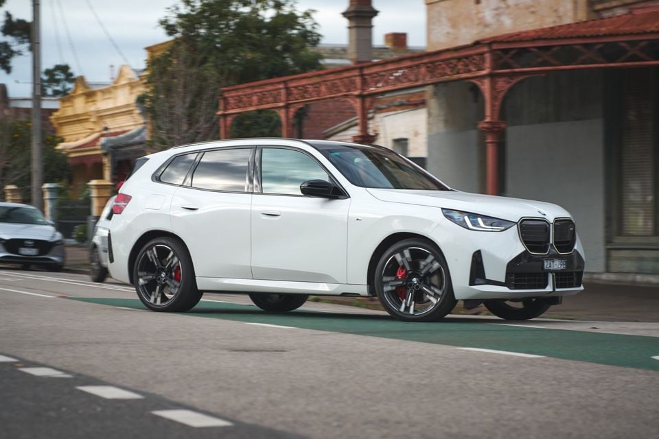 A white BMW X3 SUV driving through an Australian street, seen from the front-side angle