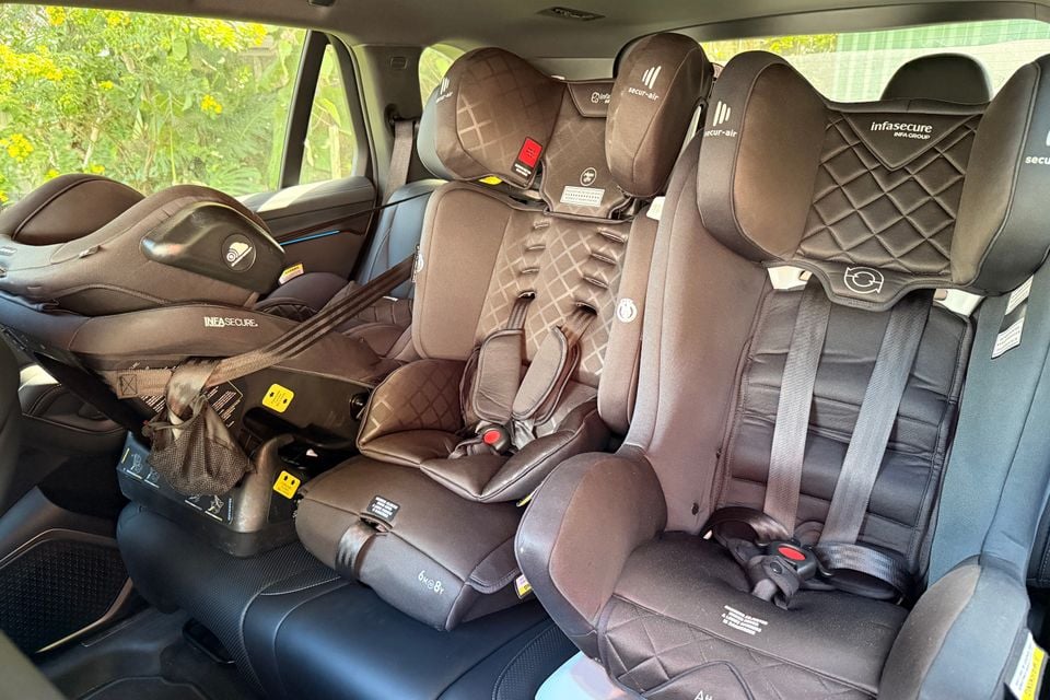 Three child car seats, including a rear-facing infant capsule, installed across the back row of a 2026 BYD Sealion 8's second-row bench.
