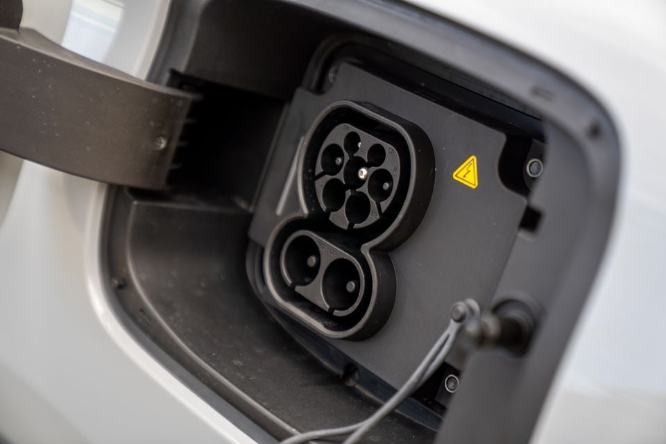 Close-up of a CCS Type 2 combined charging port on a white electric vehicle, with the charge flap open