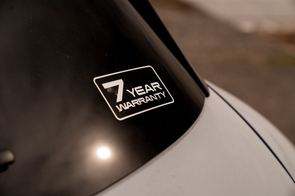 A '7 Year Warranty' sticker on the windscreen of a white Chery Tiggo 9