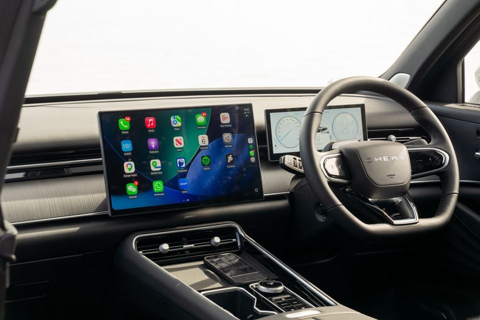 Interior of a Chery Tiggo 9 showing the large central touchscreen displaying Apple CarPlay, the digital instrument cluster, and steering wheel with Chery logo