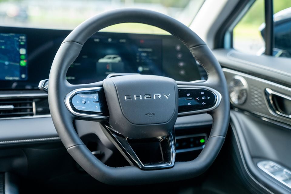 The Chery-branded steering wheel inside a 2026 Chery E5, with the digital instrument cluster and infotainment screen visible in the background.