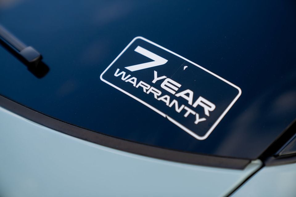 A 7 Year Warranty sticker on the windscreen of a light blue Chery E5