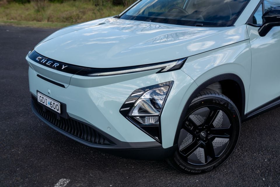Front of a light green Chery E5 SUV showing the grille, LED headlights, and alloy wheels, parked on a road