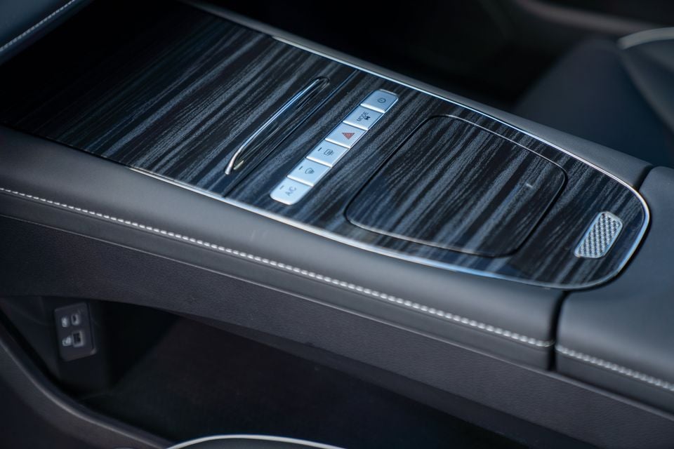 Interior centre console of the 2026 Chery E5 showing wood-look trim, climate control buttons including A/C, hazard light switch, and a touchpad-style gear selector